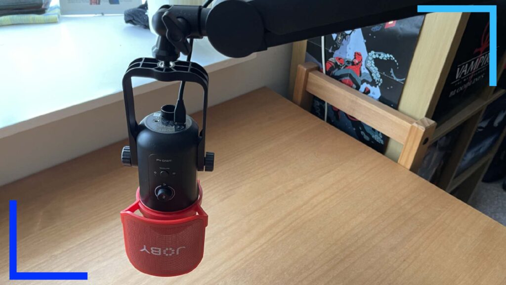 Close-up photo of the JOBY Wavo Boom Arm hanging over an oak desk.