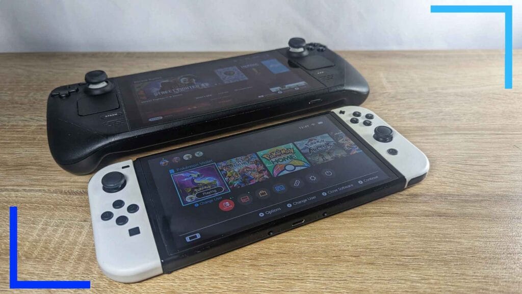 Photo of the Steam Deck lying down next to a Switch OLED at an angle with white joy con controllers.