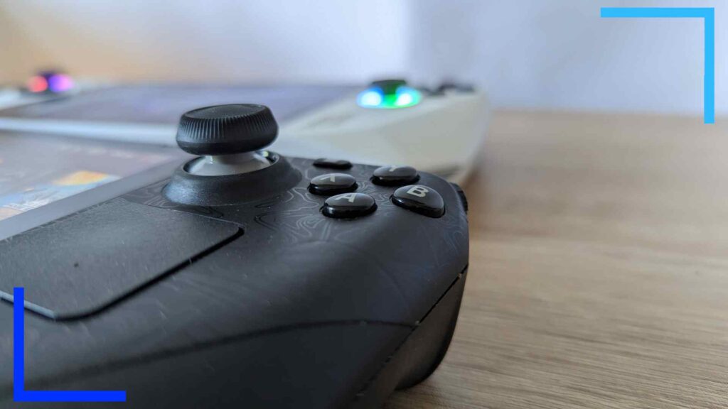 Close-up photo of the left analog stick on the Steam Deck. In the background, a blurred ASUS ROG Ally can be seen.