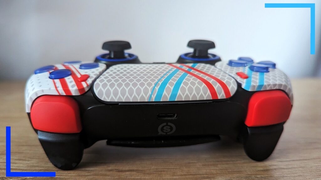 Close up photo of the Scuf controller from the top, showing the red bumpers, black triggers, and white with blue and red stripes touchpad.