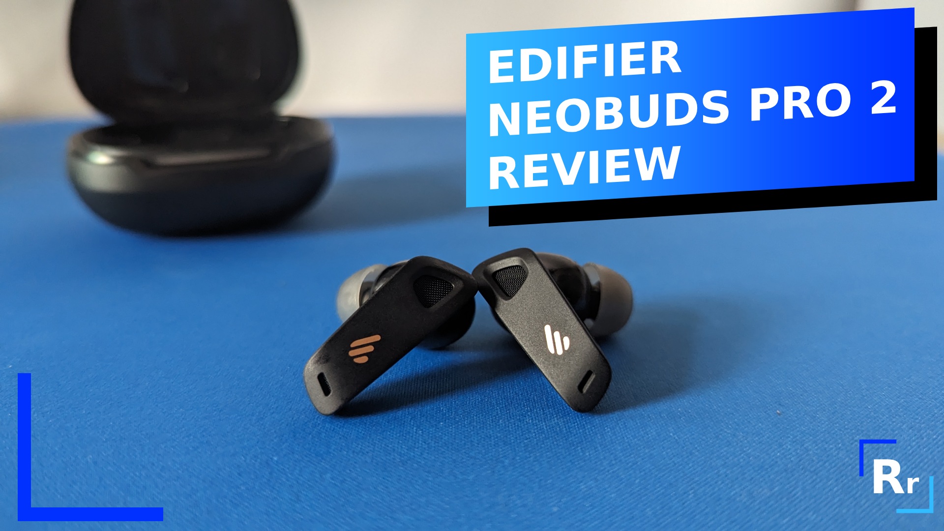 Photo of the NeoBuds Pro 2 out of the box on a blue deskpad. The text reads "Edifier NeoBuds Pro 2 review."