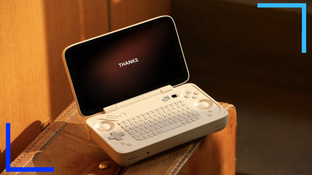 The white AYANEO KB sits on an oak colored table.