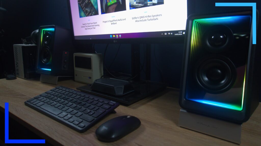 A black keyboard sits on a table in front of a mointor with the RetroResolve webiste open. To the left and right, the two QR65 speakers can be seen.