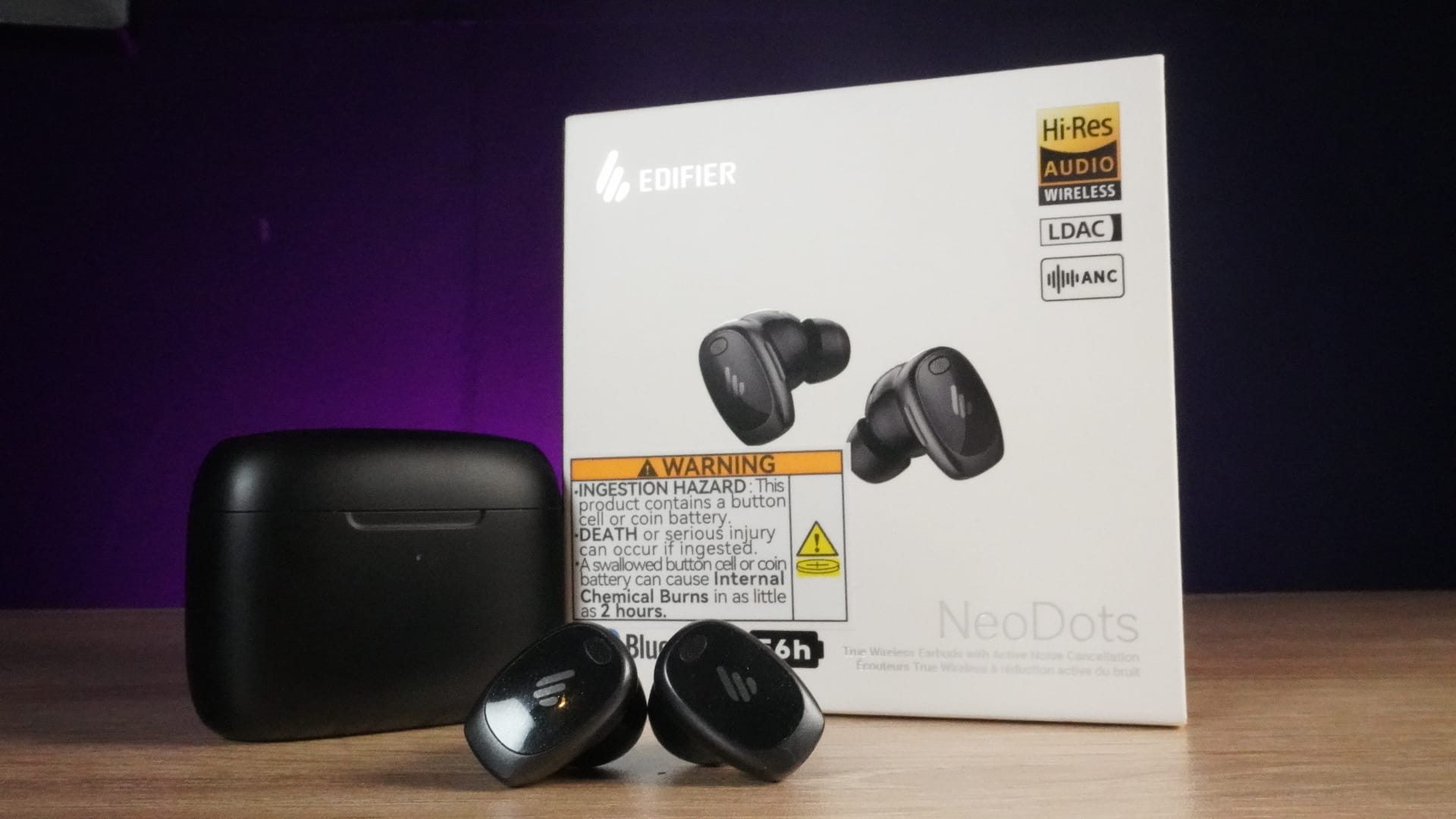 The Edifier NeoDots in front of the black charging case (left) and the main packaging (right).