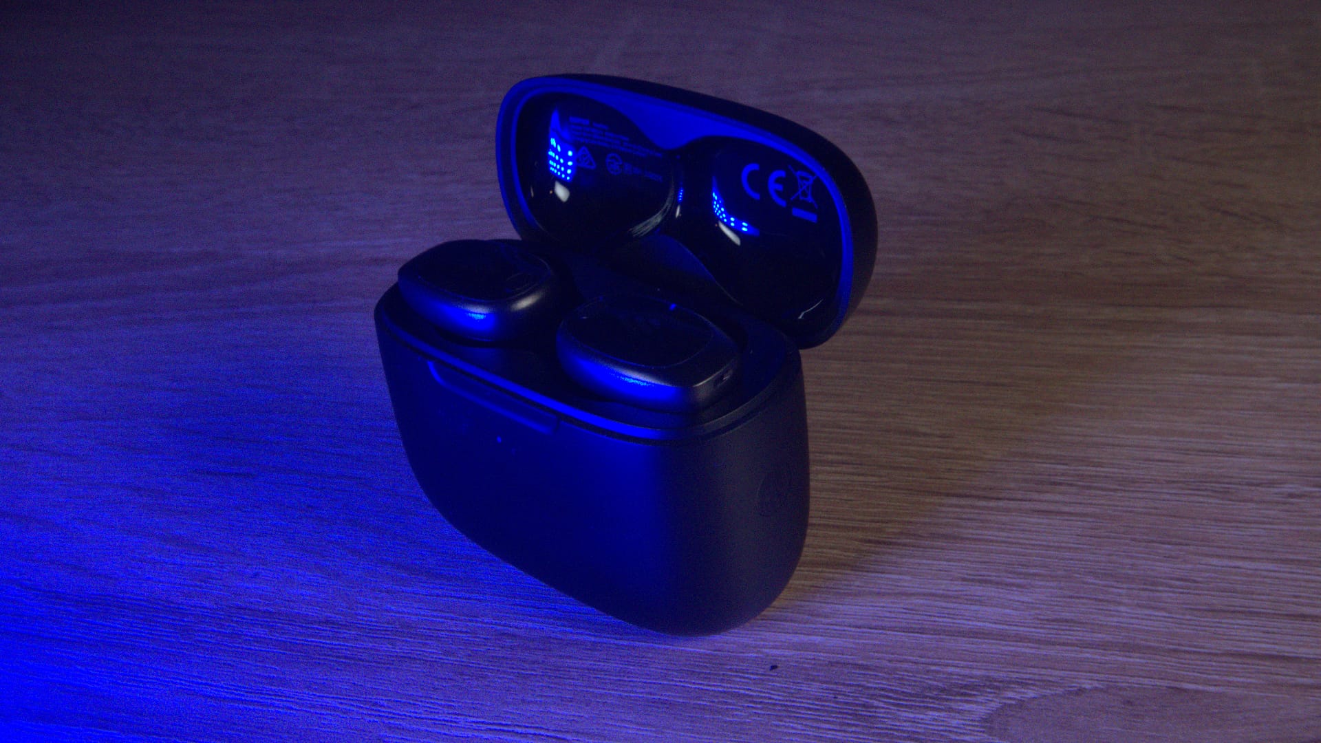 The Edifier NeoDots on an oak table bathed in blue light.