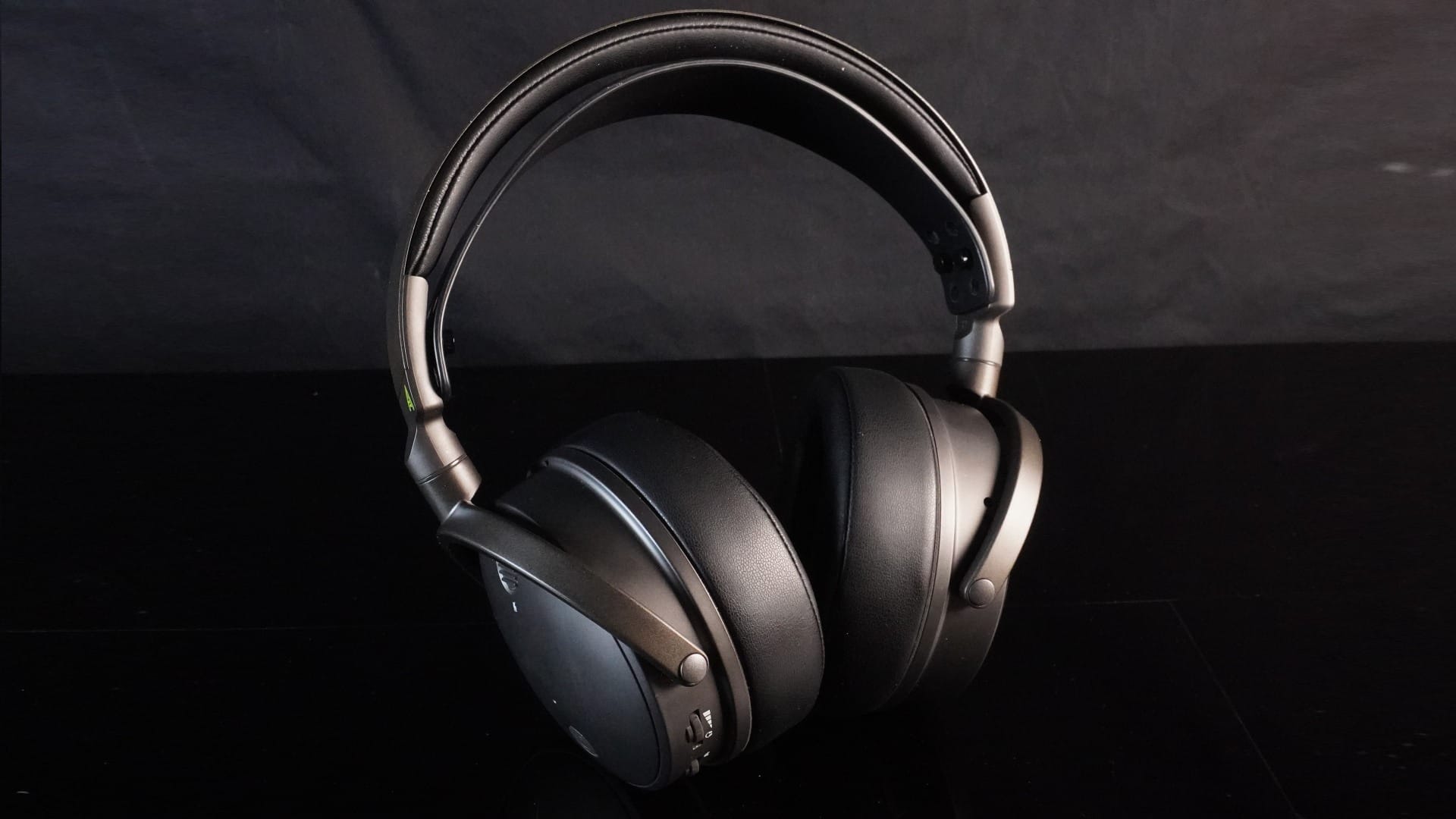 Zoomed out photo showing the black Audeze Maxwell on a black glass-like table.